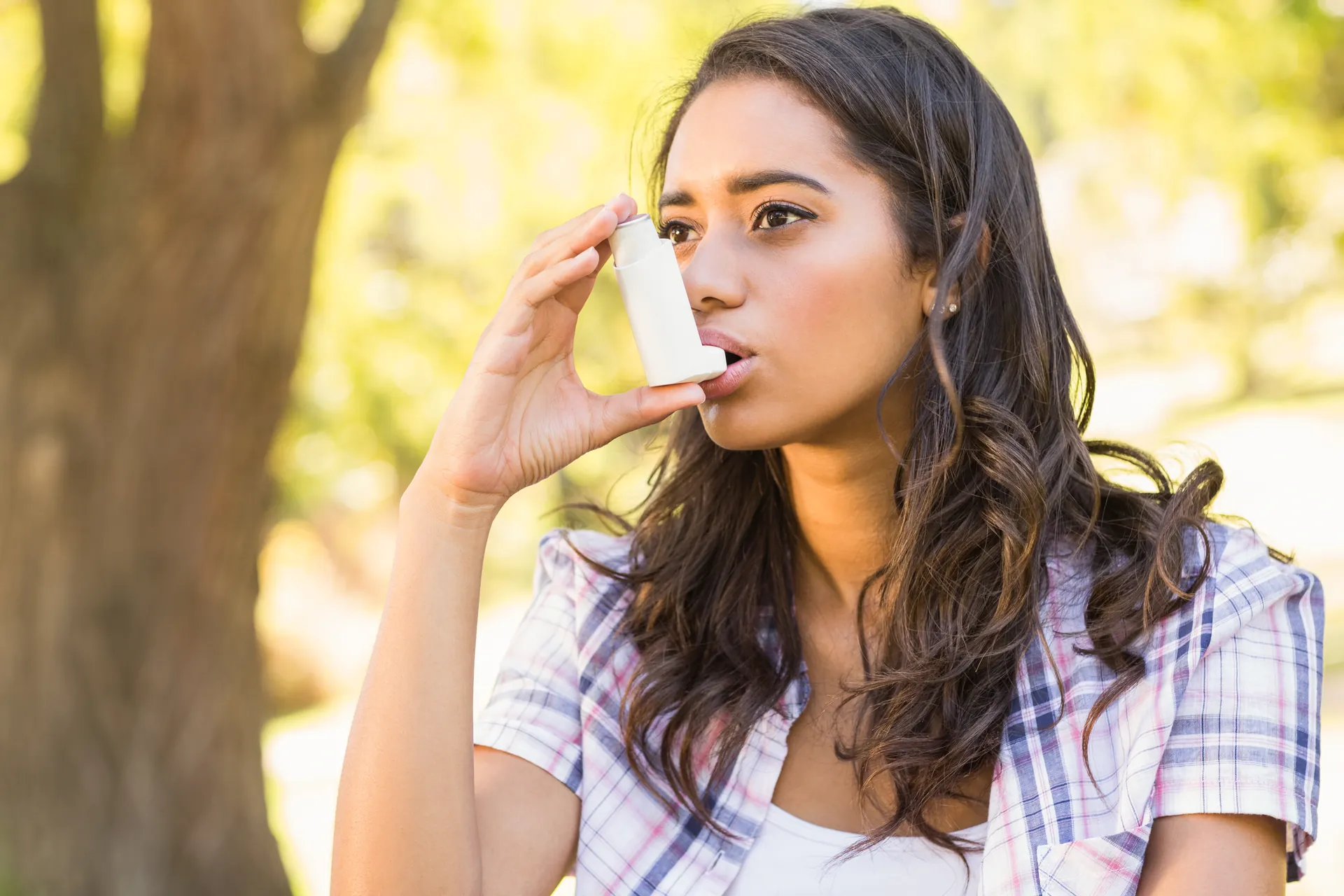 Young woman using an inhaler outdoors